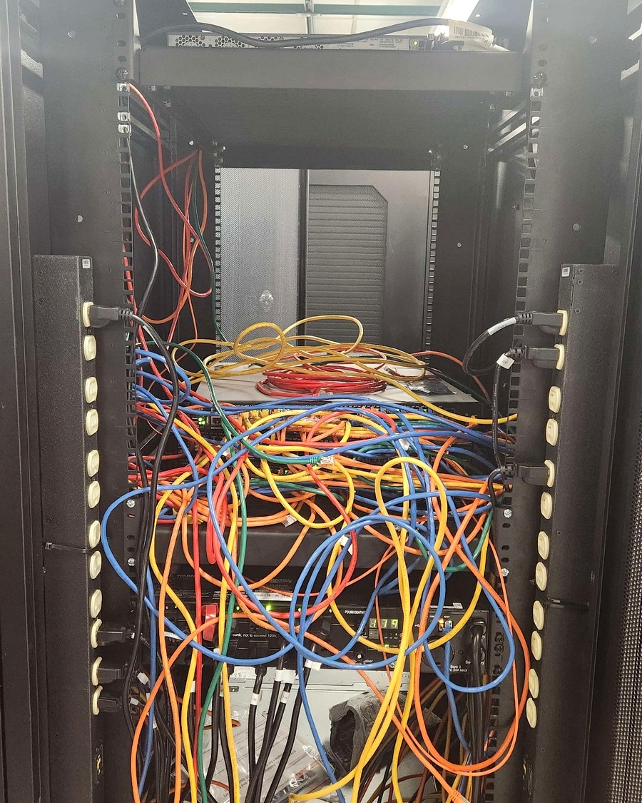 Disorganized network rack with tangled cabling before remediation